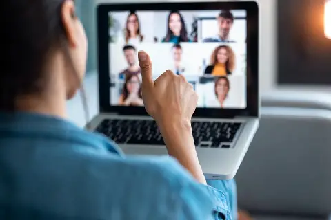 Business woman making video call and showing thumb up to laptop on the online briefing while sit on sofa at home.